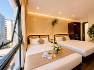 a hotel room with two beds and a window at LAVISH OCEAN INN Đà Nẵng in Danang