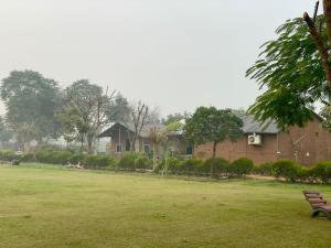 a park with a bench in front of a building at Rupani Dhani Farm Stay in Gurgaon