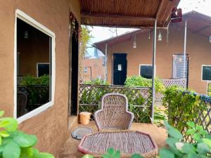 a rattan chair sitting on the porch of a house at Rupani Dhani Farm Stay in Gurgaon