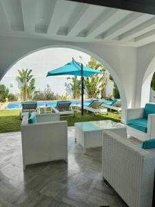 a patio with chairs and an umbrella and a pool at Villa Sky in Bin Rhilouf