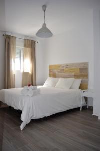 una camera da letto con un grande letto bianco con testiera in legno di Apartamento Flamingo Beach a Benalmádena