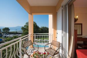 a balcony with two chairs and a view of the ocean at Sunset Hotel in Corfu