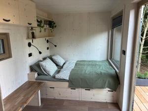 a bed in a tiny house with a window at Maringotka Na mezi in Maršovice