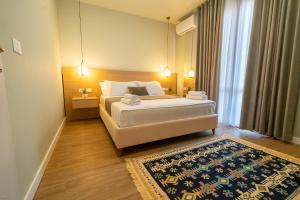 a bedroom with a large white bed and a rug at Lùmar Hotel in Vlorë