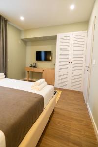 a hotel room with a bed and a flat screen tv at Lùmar Hotel in Vlorë