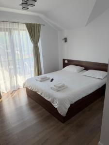 a bedroom with a bed with white sheets and a large window at Casa Lye in Vişeu de Sus