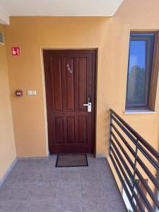 a wooden door on a building with a balcony at Six Apartman in Bükfürdő