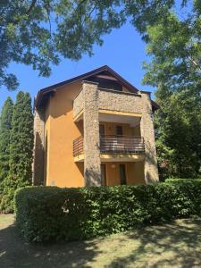 a building with a balcony and some bushes at Six Apartman in Bükfürdő