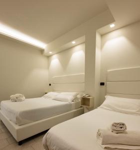 a bedroom with two beds with white sheets and towels at Hotel Twins in Vasto