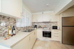 a kitchen with white cabinets and a stainless steel refrigerator at Melograno in Markopoulo