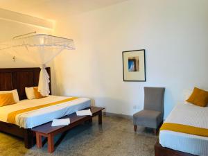 a hotel room with two beds and a chair at City Hub Transit in Katunayaka