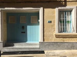 une porte bleue et une fenêtre sur un bâtiment dans l'établissement Birgu Studio Maisonette, à Il-Birgu