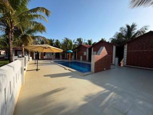 a swimming pool next to a house with a fence at Baga beach heritage resort in Calangute