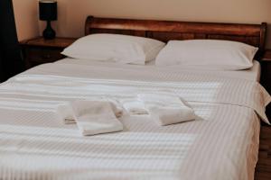 a white bed with two white towels on it at Pensiune Restaurant ROUTE60 in Ciucea