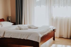 a bed with two towels on it in front of a window at Pensiune Restaurant ROUTE60 in Ciucea +39 photos