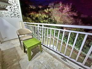 a chair with a green stool on a balcony at Arch Place in Gurgaon +7 photos