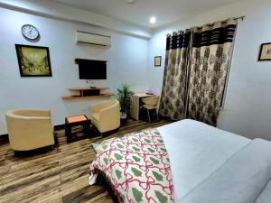 a bedroom with a bed and a desk and a tv at Arch Place in Gurgaon