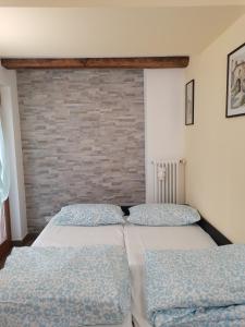 a bedroom with two beds and a brick wall at Nancy House in Longarone