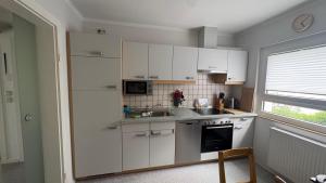 a kitchen with white cabinets and a sink and a window at Ferienwohnung Wolff, Kelkheim in Kelkheim +26 photos