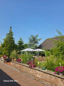 a garden with flowers and umbrellas on a brick wall at Eventhotel Moment in Sande