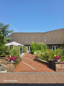 a brick walkway in front of a house with flowers at Eventhotel Moment in Sande +4 photos