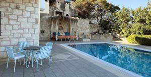 a patio with a table and chairs next to a pool at Bliss House Villa in Plaka