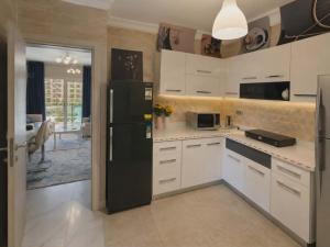 a kitchen with a black refrigerator and white cabinets at ابراج الداون تاون العلمين الجديده Luxury Apartment In Downtown New Alamein in Ad Darāzīyah