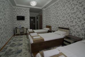 a bedroom with three beds and a wall with wallpaper at Hotel Ayyub Sultan in Urganch