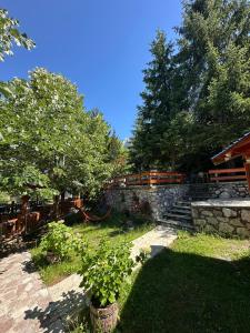 a garden with a stone wall and some trees at Natyra balcony in Valbonë