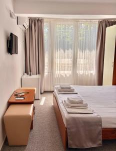 a bedroom with two beds and a table and a window at Vila Aqua in Eforie Sud