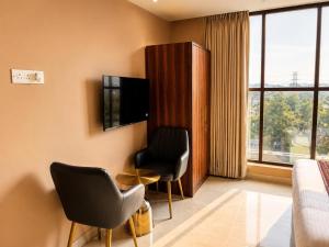 ein Hotelzimmer mit zwei Stühlen, einem Tisch und einem Fernseher in der Unterkunft Hotel Supreme Regency in Ludhiana