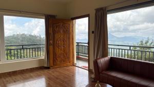 a living room with a couch and large windows at Elysian Villa by Hostel Jerusalem in Kodaikānāl