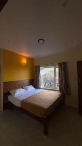 a bedroom with a large bed with a window at Elysian Villa by Hostel Jerusalem in Kodaikānāl