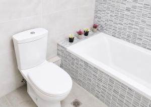 a white bathroom with a toilet and a bath tub at Ionian Studio in Lixouri