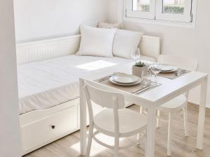 a white bedroom with a table and a bed at Ionian Studio in Lixouri +4 photos