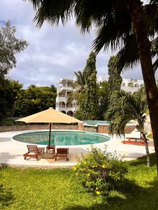 a swimming pool with two chairs and an umbrella at Beverly Suites - Two Bedroom Apartment 2-5min to Beach in Malindi