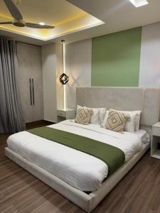a bedroom with a large white bed with a green blanket at Designer Boutique Hotel Serviced Apartments Bahria Town Islamabad & Rawalpindi - LMY in Rawalpindi