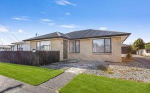 a brick house with a fence in a yard at Welcome to Wigan in Gore