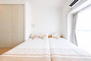 a bedroom with a bed with white sheets and a window at 宇都宮ハウスシラユリ in Utsunomiya