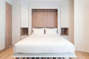 a bedroom with a large bed with white sheets at City Pop 2Night Geneva - Self check-in in Geneva