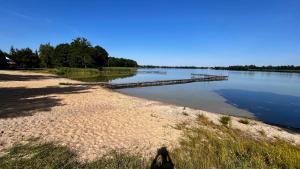 a beach with a dock in the middle of a lake at NASZE BIAŁE pokój 2 osobowy in Okuninka +3 photos