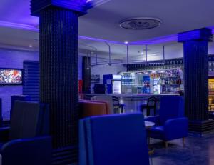 a restaurant with blue chairs and a bar with purple lighting at Novatel Radisson Lekki in Lekki