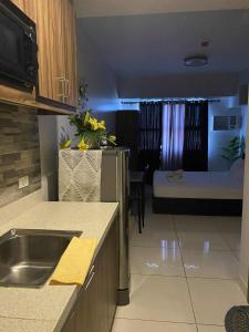 a kitchen with a sink and a room with a bed at Horizons 101 in Cebu City