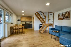 a living room with a blue couch and a kitchen at Domki przy Skarpie in Lądek-Zdrój