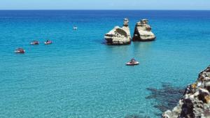 a group of boats in the water near some rocks at Lumina Rooms in Torre dell'Orso