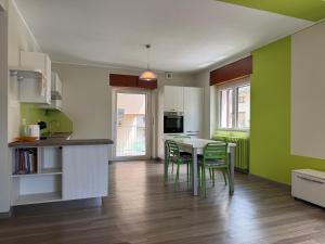 a kitchen with green walls and a table and chairs at La Terrazza di Gino in Grosio