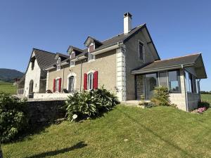 a house with red doors on a grass field at Larrouy in Asson