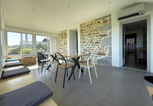 a dining room with a table and chairs and a stone wall at Larrouy in Asson