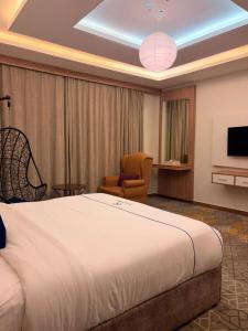 a hotel room with a bed and a chair and a tv at Golden New Tulip in Abha