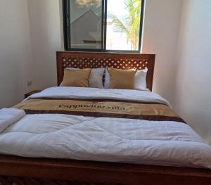 a large bed with a wooden headboard in a bedroom at Cappuccinovilla in Paje +7 photos
